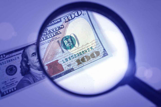 Cashier checking a U.S. $100 bill at a small business register